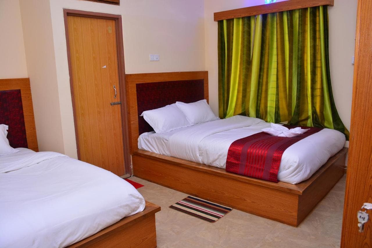Family room interior with a single bed and an adjacent double bed, wood headboards, and green curtains