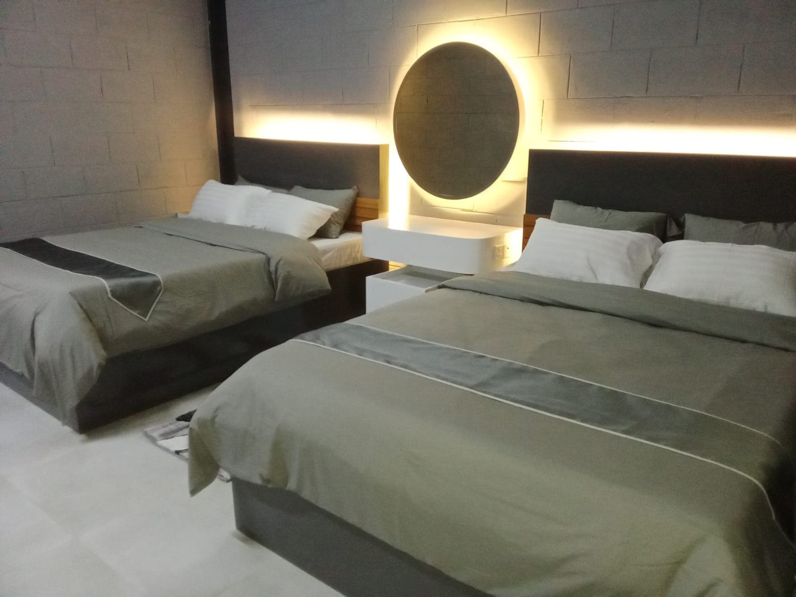 A twin-bed room at Oronner Din Ratri Resort with a backlit circular mirror between the headboards