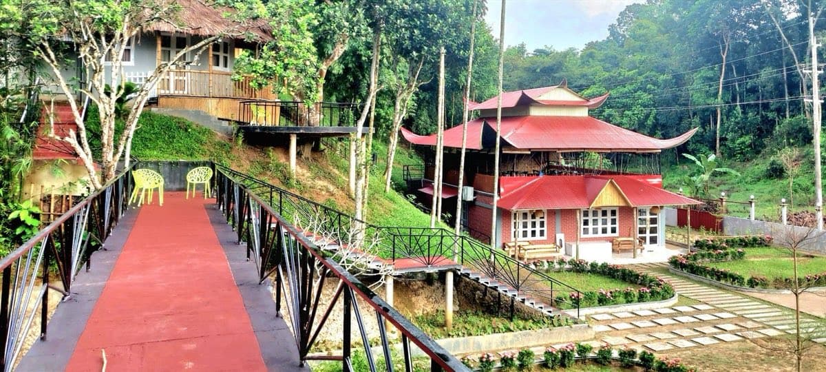 Phayre's Woods Resort's raised walkway leading to its red-roofed pavilion among trees