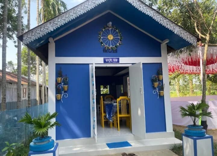 Small blue outbuilding on the grounds labelled "রান্না ঘর" (kitchen room) in Bangla, with a dining table visible through the open door