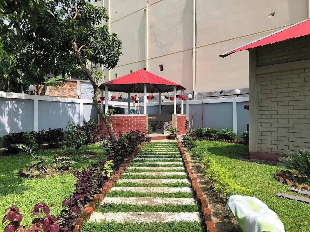 Garden pathway of stepping stones leading to a red-roofed gazebo surrounded by landscaped plants